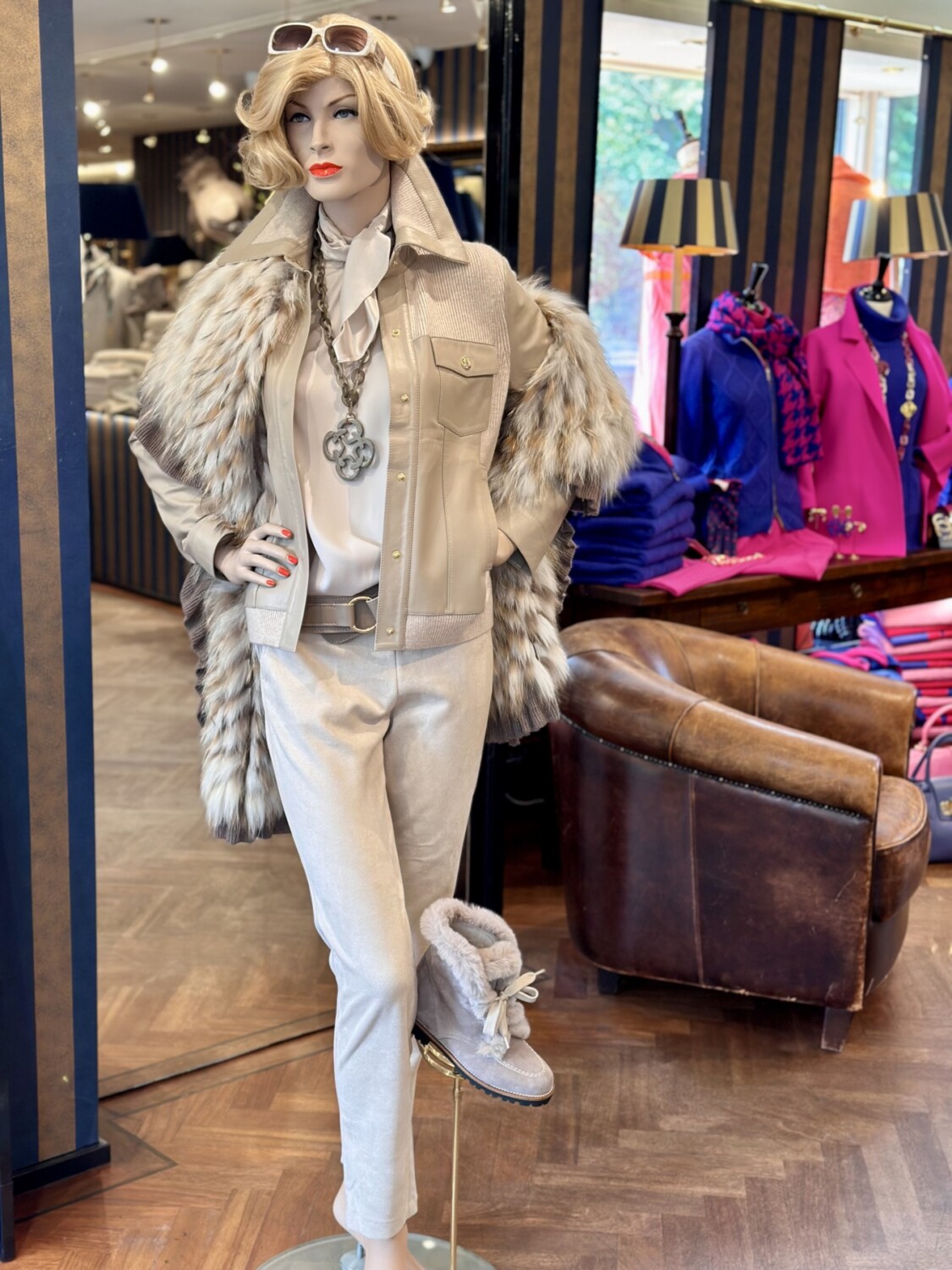 Blonde mannequin met beige kleding en sjaal, in modieuze winkeldisplay voor high-end mode.