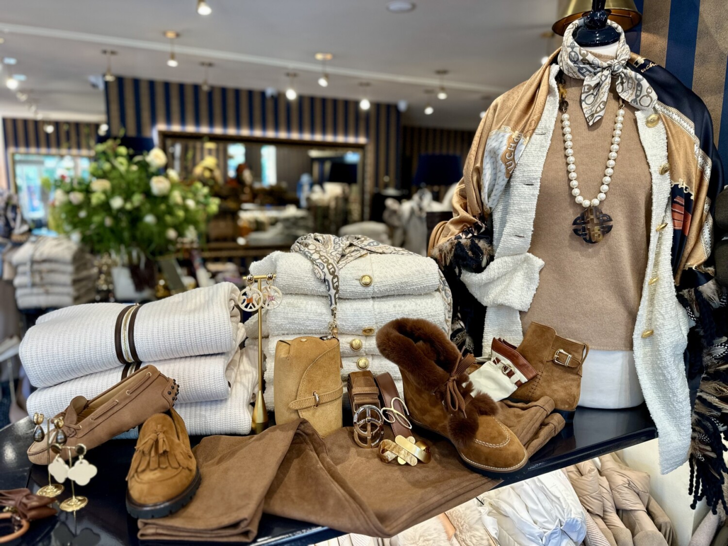 Witte en bruine herfstoutfits en accessoires uitgestald in een modieuze winkel.