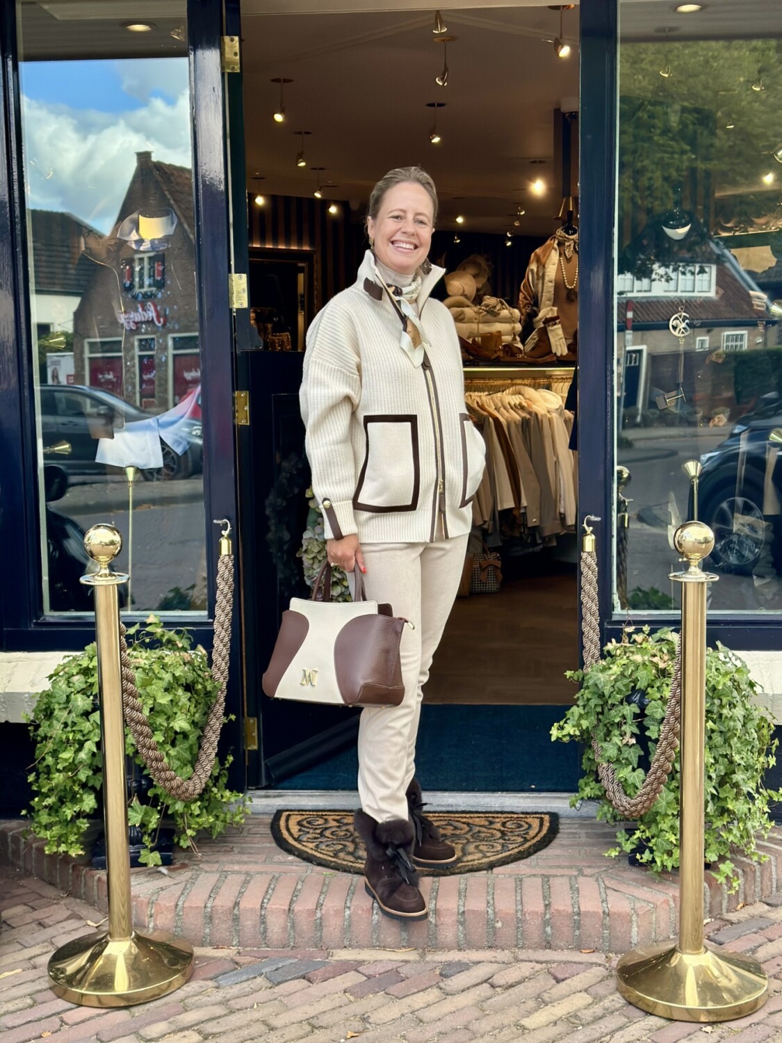 Elegante vrouw met modieuze beige en bruin outfit voor de boetiek Modici in Nederland.