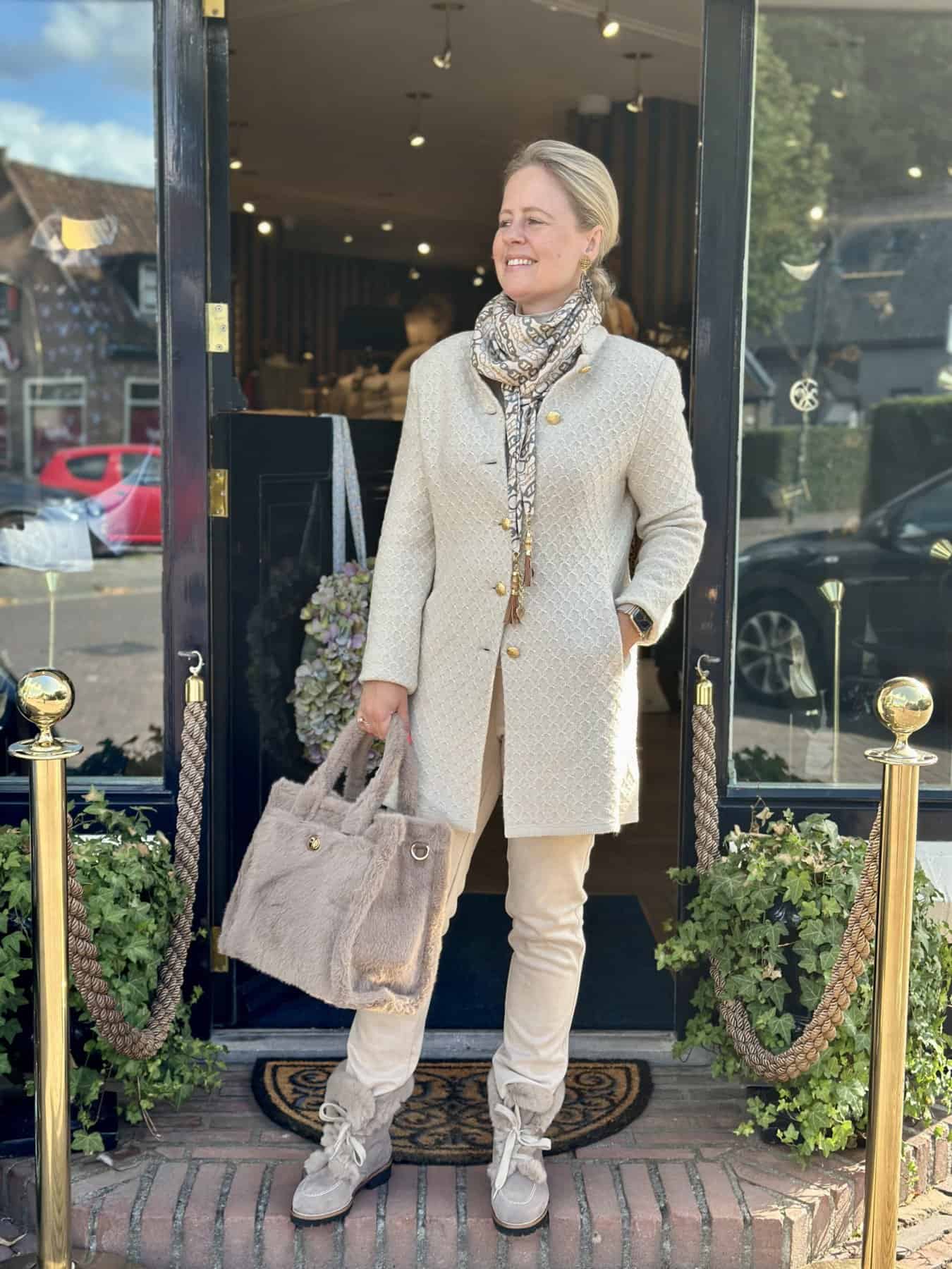 exclusief beige dames vest bij modici laren verkrijgbaar ook in groten maten Luxe damesoutfit met beige jas en zachte tas voor elegante herfstlook.