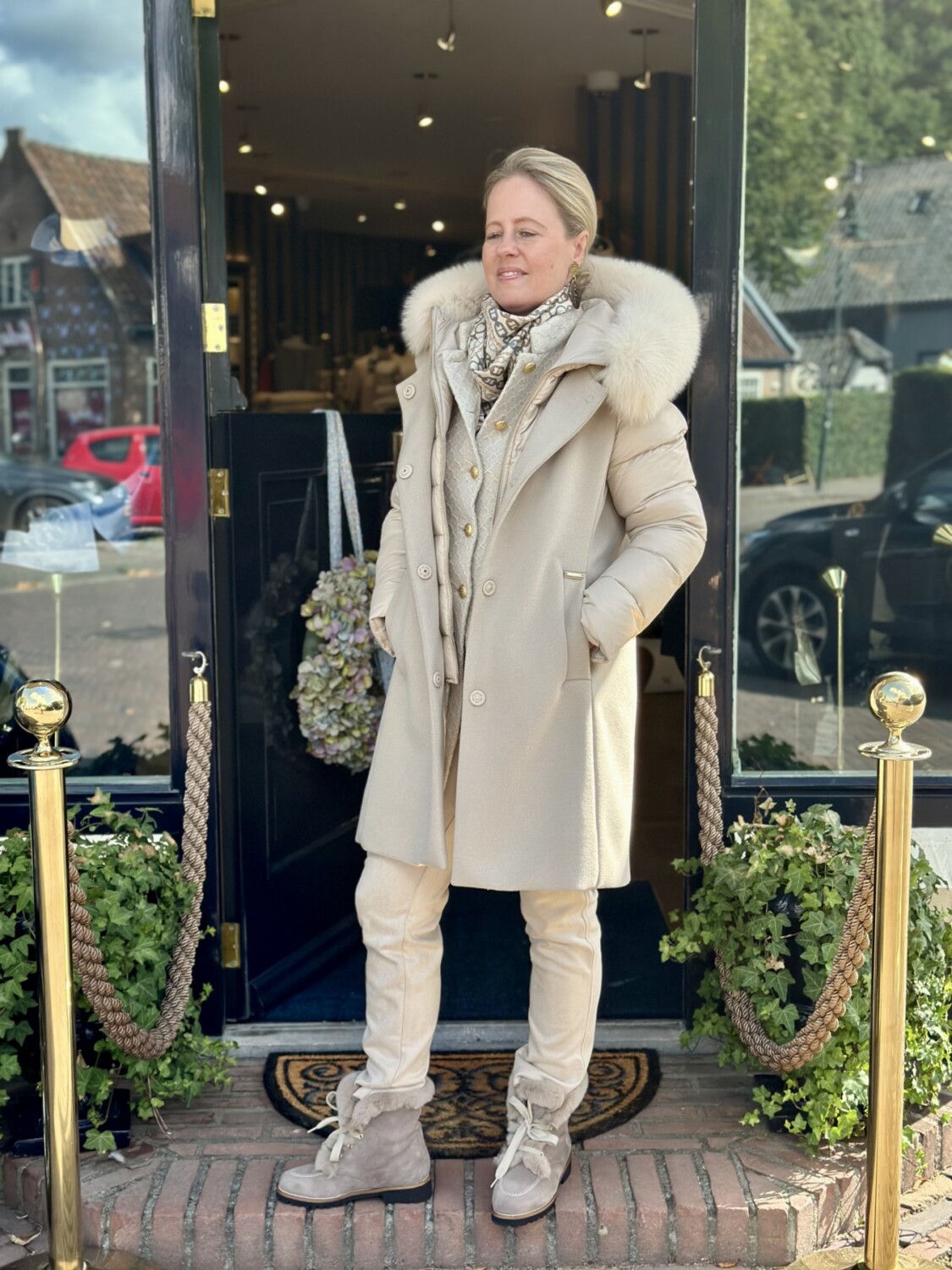 Luxueuze beige winterjas met capuchon en bontkraag, perfect voor een modieuze koude dag.