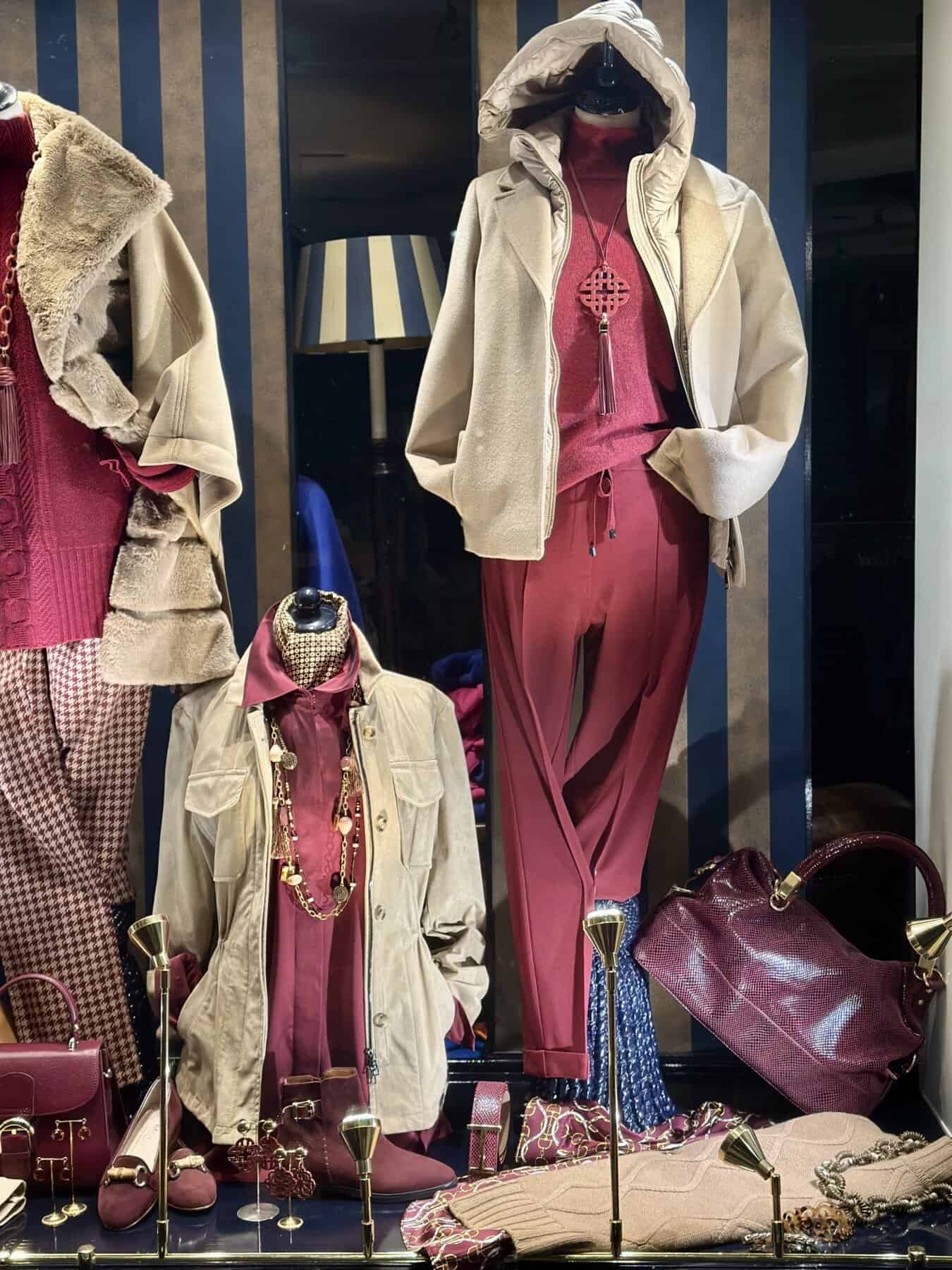 Leren mantel en rode sportieve outfits, modieuze accessoires, handbagage en schoenen voor dames, stijlvolle winkel display met modestijlen.